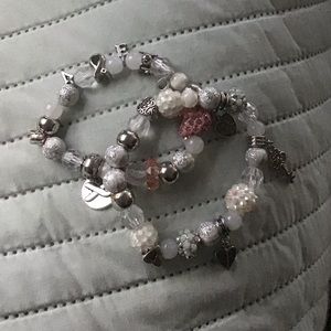 Bracelets are white, pink, silver, with charms.
